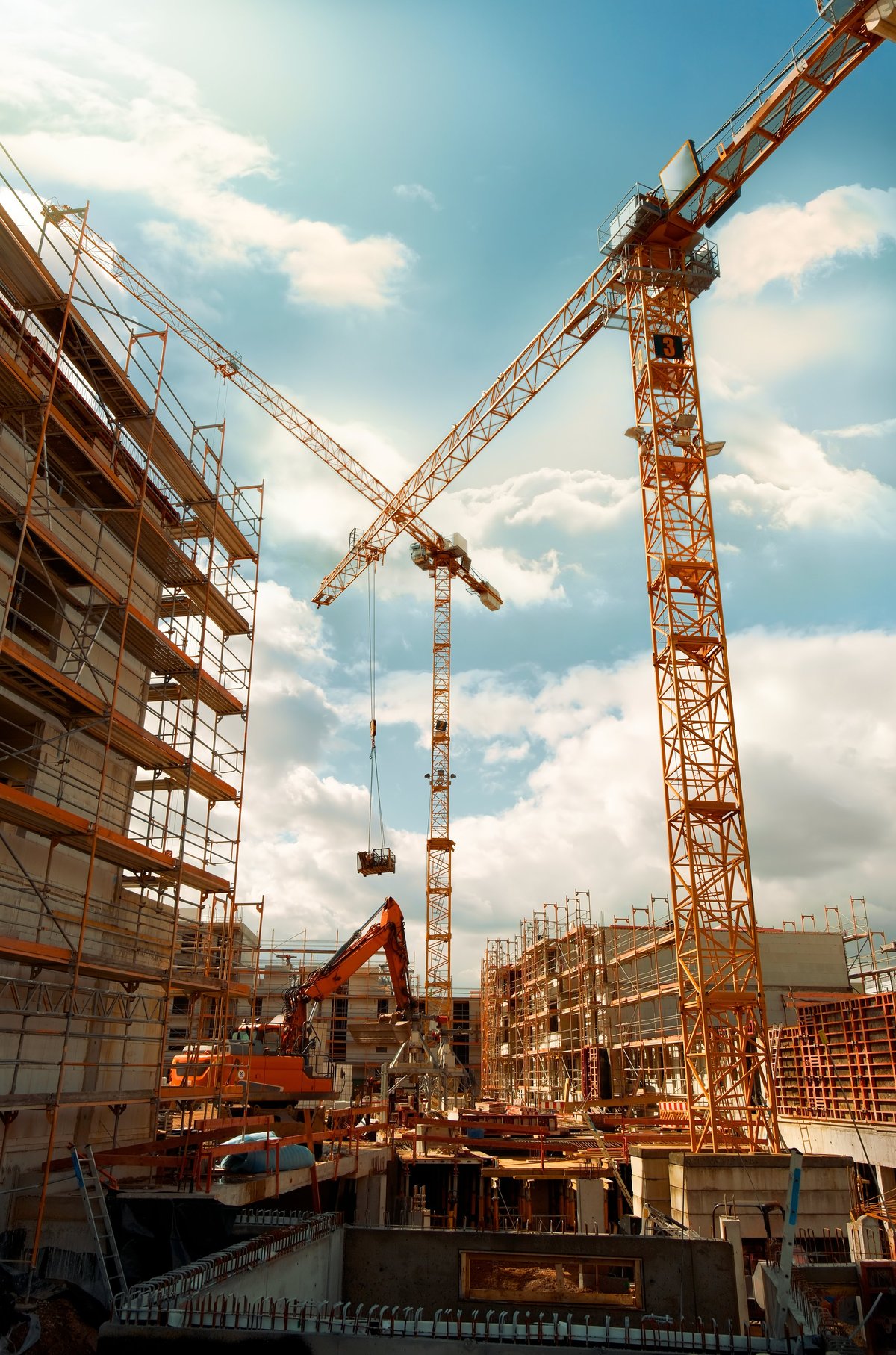 Commercial construction site with tower cranes against a dramatic sky